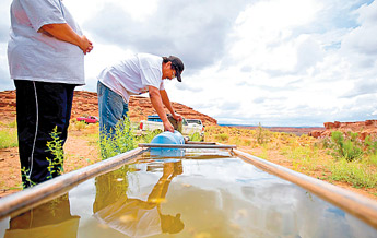 Larry Tohannie fills a water jug along with his wife Rolanda at Box Springs in Black Falls, Ariz. A sign near the well indicates that water from the well is undrinkable, but due to their distance from clean water, the Tohannie's have little choice but to drink it.. — © 2009 Gallup Independent / Brian Leddy 