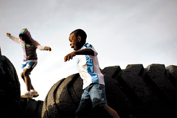 Evensky Kros, 8, foreground, and his sister Genese Kros,10, navigate the tires at the Rehoboth campus playground, Thursday. Evensky, Genese and sister Lily, 13, not pictured have been adopted from Haiti by Karen Kros in Rehoboth. — © 2009 Gallup Independent / Adron Gardner