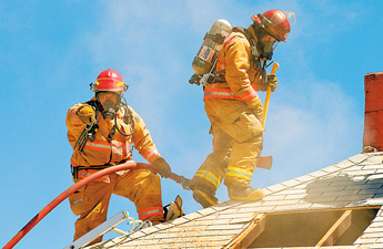 A Gallup firefighter signals to others on the ground while another handles the ax responding to a fire off Coronado in Gallup on Friday. — © 2009 Gallup Independent / Adron Gardner