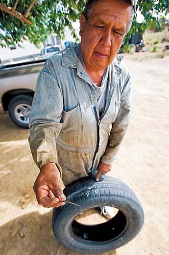 Deer Springs resident Kenneth Yazzie show a piece of metal that he pulled from one of his tires Wednesday. Yazzie and other area residents have suffered several flat tires because of the conditions of Deer Springs Loop. — © 2009 Gallup Independent / Cable Hoover