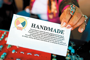 A jewelry vendor at Earl's Restaurant shows the "Handmade" tag that the Council for Indigenous Arts and Culture requires vendors to display with their goods. — © 2009 Gallup Independent / Cable Hoover