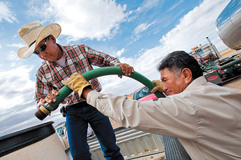 Edison Begay, right, of the Navajo Tribal Utility Authoriy helps Gerome Begay fill his water barrels from a large tanker in Dilkon Tuesday. The Navajo Nation Department of Emergency Management sent tankers throughout the region to help relieve a water shortage. — © 2009 Gallup Independent / Cable Hoover 