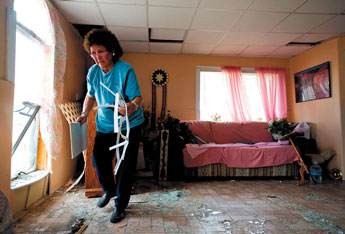 Emily Joe cleans up glass and debris from her home on Hard Ground Canyon Road on Monday afternoon. A violent wind storm, called a microburst, was thought to be the culprit that damaged the house. — © 2009 Gallup Independent / Brian Leddy