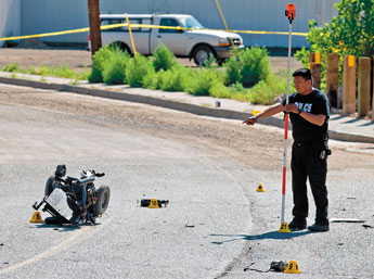 Francie Martinez, a crash reconstructionist with the Gallup Police Department, works a scene on Aztec Avenue on Thursday morning. An allegedly intoxicated male driver struck two pedestrians in wheelchairs as they crossed the road Friday around 9 p.m. — © 2009 Gallup Independent / Brian Leddy 