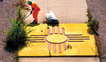 A prisoner from the state department of corrections chops down weeds along the zia symbol adorning Interstate 40 off Maloney on Tuesday.— © 2009 Gallup Independent / Adron Gardner