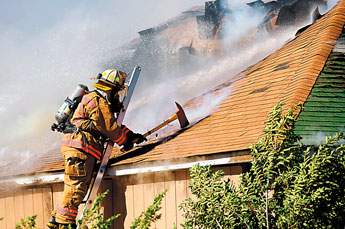 A Gallup firefighter opens a hole with an ax in the roof of a smoldering residence on Aztec on Friday. — © 2009 Gallup Independent / Adron Gardner 