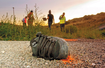 The shoe from one of two victims in a double vehicular fatality lies yards from her body and investigators examining the scene on the U.S. 491 intersection in Yatahey on Friday. — © 2009 Gallup Independent / Adron Gardner