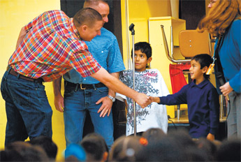 Kevin, left, and Ryan Menapace are greeted by Tito, right, and Isaac Bustinza during an assembly held to honor the Menapaces at Lincoln Elementary Friday. The two men rescued the boys and their sibling from their burning home Aug. 7. — © 2009 Gallup Independent / Cable Hoover