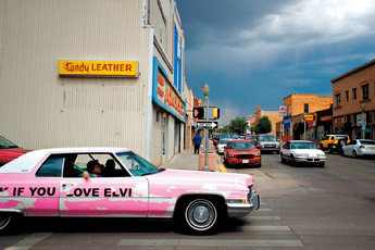A pink Cadillac with a sign on the side that says "Honk If You Love Elvis" cruises downtown Gallup on Thursday afternoon as a thunderstorm looms on the horizon. — © 2009 Gallup Independent / Brian Leddy