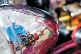 Emerson Curley, left, and his daughter Emerlynn Curley are reflected in the chrome headlight of a hot rod on display at the Route 66 Ford-Fest car show at Gurley Ford Saturday. — © 2009 Gallup Independent / Cable Hoover