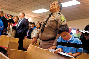 Seven-year-old Joshua Nelson reads along in a hymnal while his father Steve sings along at Emmanuel Baptist Church on Sunday. The Nelson family traveled from Crownpoint to attend the annual Law Enforcement Appreciation Day service at the church. — © 2009 Gallup Independent / Brian Leddy 