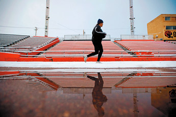 Despite an early morning snow, Maureen Klah jogs the track at Public School Stadium in Gallup on Wednesday as a fall snowstorm rolled through the area. — © 2009 Gallup Independent / Brian Leddy 