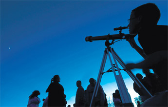 Eleven-year-old Joshua Knotts peers at the moon through his newly won telescope in twilight at the Northwest New Mexico Visitor Center on Saturday in Grants. — © 2009 Gallup Independent / Adron Gardner 