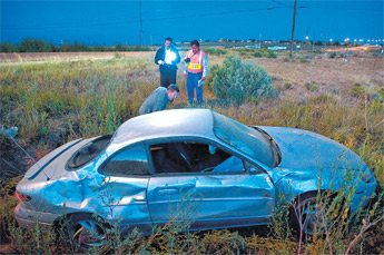 Investigators examine the damaged car of a suspect in a double hit-and-run fatality on New Mexico Highway 264 in Yatahey in this photo taken Aug. 21. — © 2009 Gallup Independent / Adron Gardner 