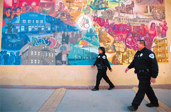 Gallup Police officers Travis Simshauser, right, and Miranda Littlefield walk past one of downtown Gallup’s many murals while on the department’s new downtown foot patrol Tuesday. — © 2009 Gallup Independent / Cable Hoover