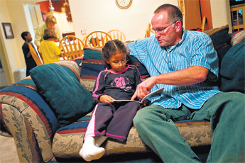 Brian Kruis helps his 6-year-old daughter Ruthann Kruis read a story at their home Friday. — © 2009 Gallup Independent / Cable Hoover 