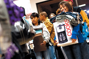 Jordan Mescal, right, carries an armload of merchandise as she waits in line to check out at JC Penney early Friday morning. Many shoppers arrived at the store as early as 4 a.m. — © 2009 Gallup Independent / Cable Hoover 