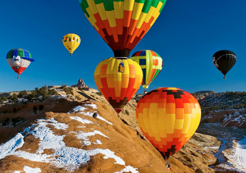 Professional photographer Barak Naggan crouches atop the red rocks in this Dec. 1, 2006, file photo to photograph the hot air balloons as they ascend around during the Red Rock Balloon Rally at Red Rock Park. — © 2009 Gallup Independent / Staff Photo