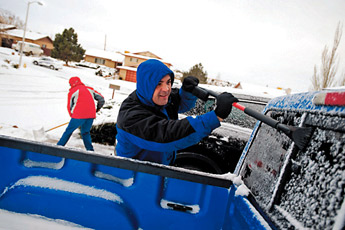 Chris Chamberlin scrapes ice from his windshield as his wife Pearl shovels snow in their driveway on Anthony Avenue on Tuesday morning. — © 2009 Gallup Independent / Brian Leddy 