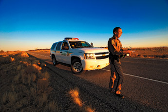 Navajo Police Officer Joel Lueppe walks along Navajo 9 near Whitehorse to write a speeding citation on December 3rd. — © 2009 Gallup Independent / Adron Gardner