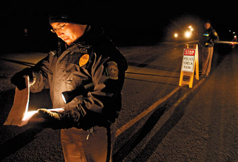 It is eight degrees above zero and Selective Traffic Enforcement Program team leader, Navajo Police Officer Custer Bryant, checks a list of outstanding warrants during a DWI checkpoint in Torreon Dec. 3rd. — © 2009 Gallup Independent / Adron Gardner