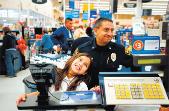 Megan Palacio smiles as her toys are rung up at Walmart with Grants Police Sgt. John Castaneda on Friday. — © 2009 Gallup Independent / Brian Leddy 