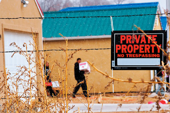 A newly posted "No Trespassing" sign hangs on the fence around Churchrock Estates as residents pack up their belongings Tuesday in Churchrock. Some of the residents evicted from their homes Monday were allowed back onto the property to pack and move their things. — © 2009 Gallup Independent / Cable Hoover