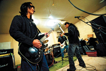 Darius Yazzie, left, strums in unison with his bandmates Everrett Jim and Gerald Sleuth of Shadow Remain during a practice set in Coolidge on Monday. — © 2010 Gallup Independent / Adron Gardner 