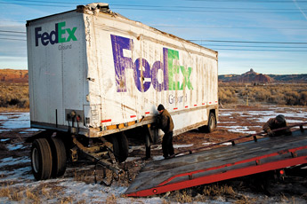 Speedway Towing employees Kevin Chavez and Frank Hernandez work on towing a Fed Ex trailer that overturned on Thursday morning near Fire Rock Casino. The trailer, driven by Billie Krantz of Dallas, Texas, overturned after she lost control of her truck while driving west on Interstate Highway 40, crossing Historic Route 66 and landing in the ditch on the north side of the road. — © 2010 Gallup Independent / Brian Leddy