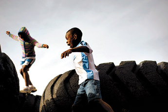 Evensky Kros, 8, foreground, and his sister Genese Kros,10, navigate the tires at the Rehoboth campus playground, Thursday. Evensky, Genese and sister Lily, 13, not pictured have been adopted from Haiti by Karen Kros in Rehoboth. &mdash;&nbsp;&copy; 2009 Gallup Independent / Adron Gardner