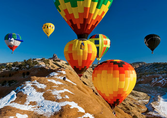 Professional photographer Barak Naggan crouches atop the red rocks in this Dec. 1, 2006, file photo to photograph the hot air balloons as they ascend around during the Red Rock Balloon Rally at Red Rock Park. &mdash;&nbsp;&copy; 2009 Gallup Independent / Staff Photo